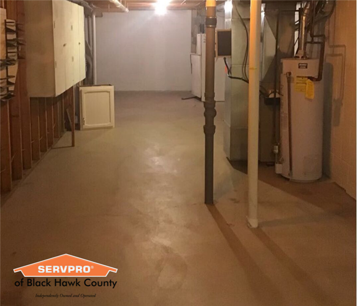 Empty basement with water heater and high ceiling.