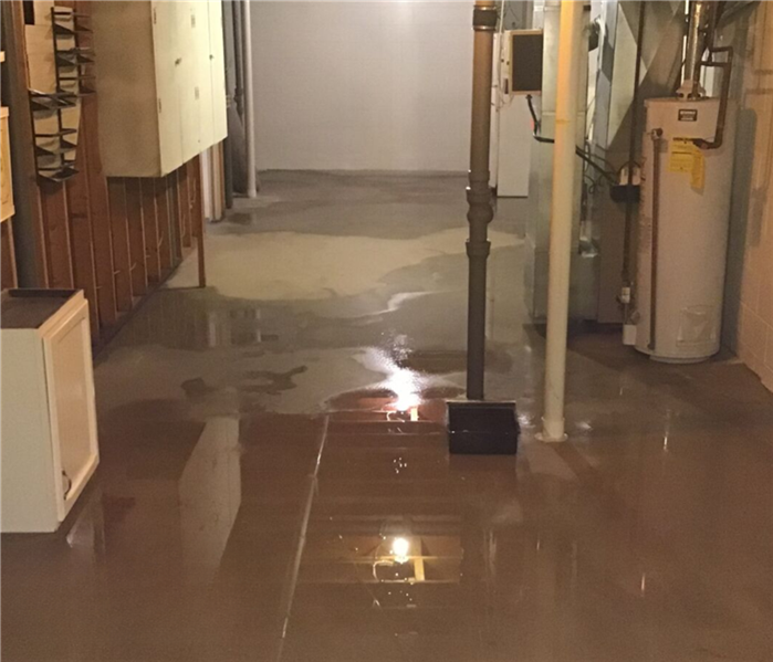 Water on cement flooring pools toward the center of the basement.