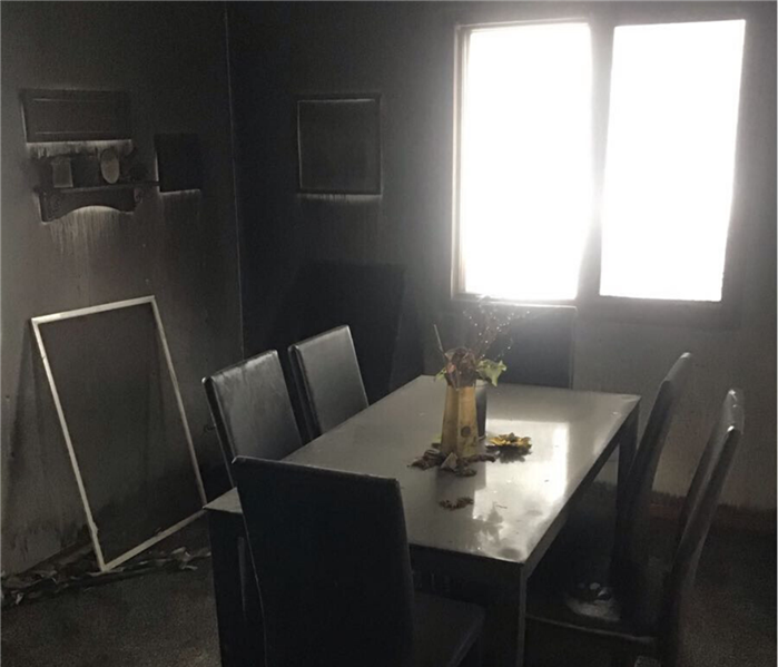 A dingy dining room with light shining through a window. Soot is everywhere.