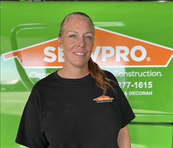 Servpro employee in front of green vehicle