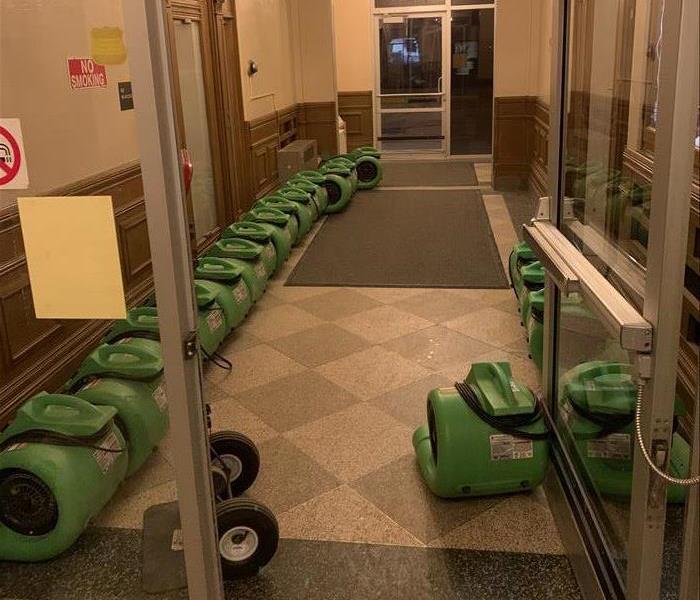 Green air movers lined up in entry.