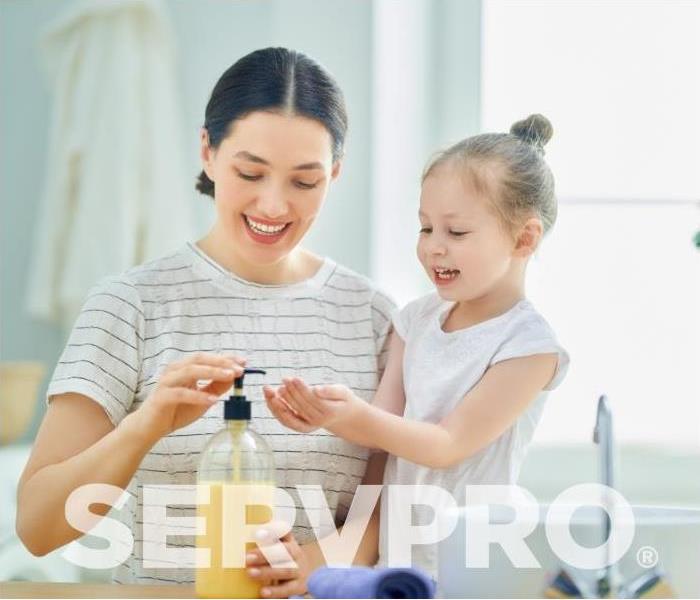 Mom helping her daughter wash her hands with the SERVPRO logo across it